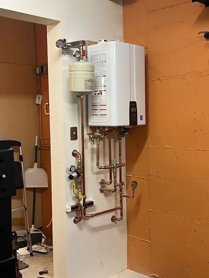 Plumbing technician inspecting water heater connections in East Lansing